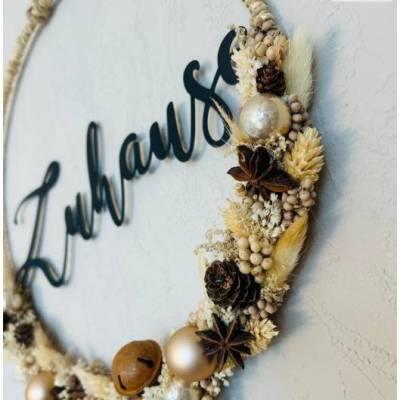 Cremefarbener Weihnachtskranz mit vielen verschieden Trockenblumen und Glöckchen in Rostoptik