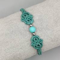zierliches Makramee Armband in türkis mit einer mattierten Acrylperle und silberfarbenen Metallperlen