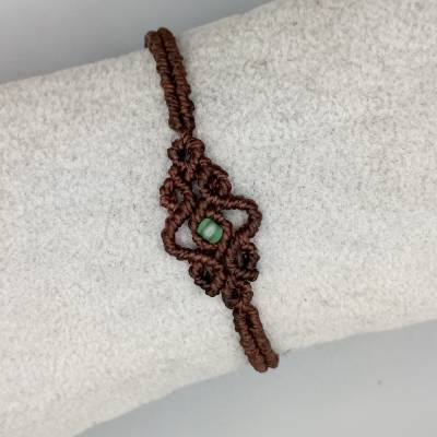 zierliches Makramee Armband in dunkelbraun mit einer grünen Glasperle