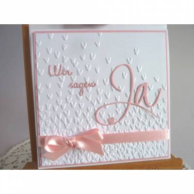 Einladungskarte zur Hochzeit in weiß/rosa, mit geprägtem Hintergrund, und *Wir sagen Ja* Schriftzug