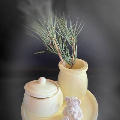 Set aus Teddy, Töpfchen und kleiner Vase auf einem runden Tablett